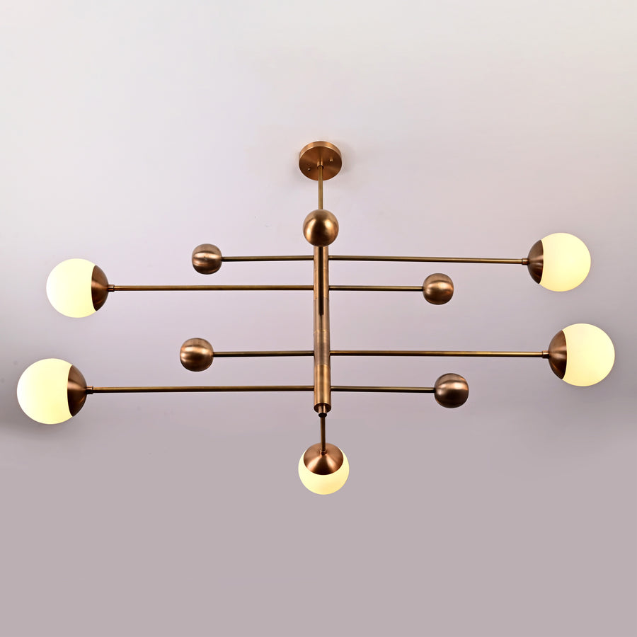 Modern 5-light brass chandelier with opal glass globes arranged on linear brass arms for balanced contemporary lighting.