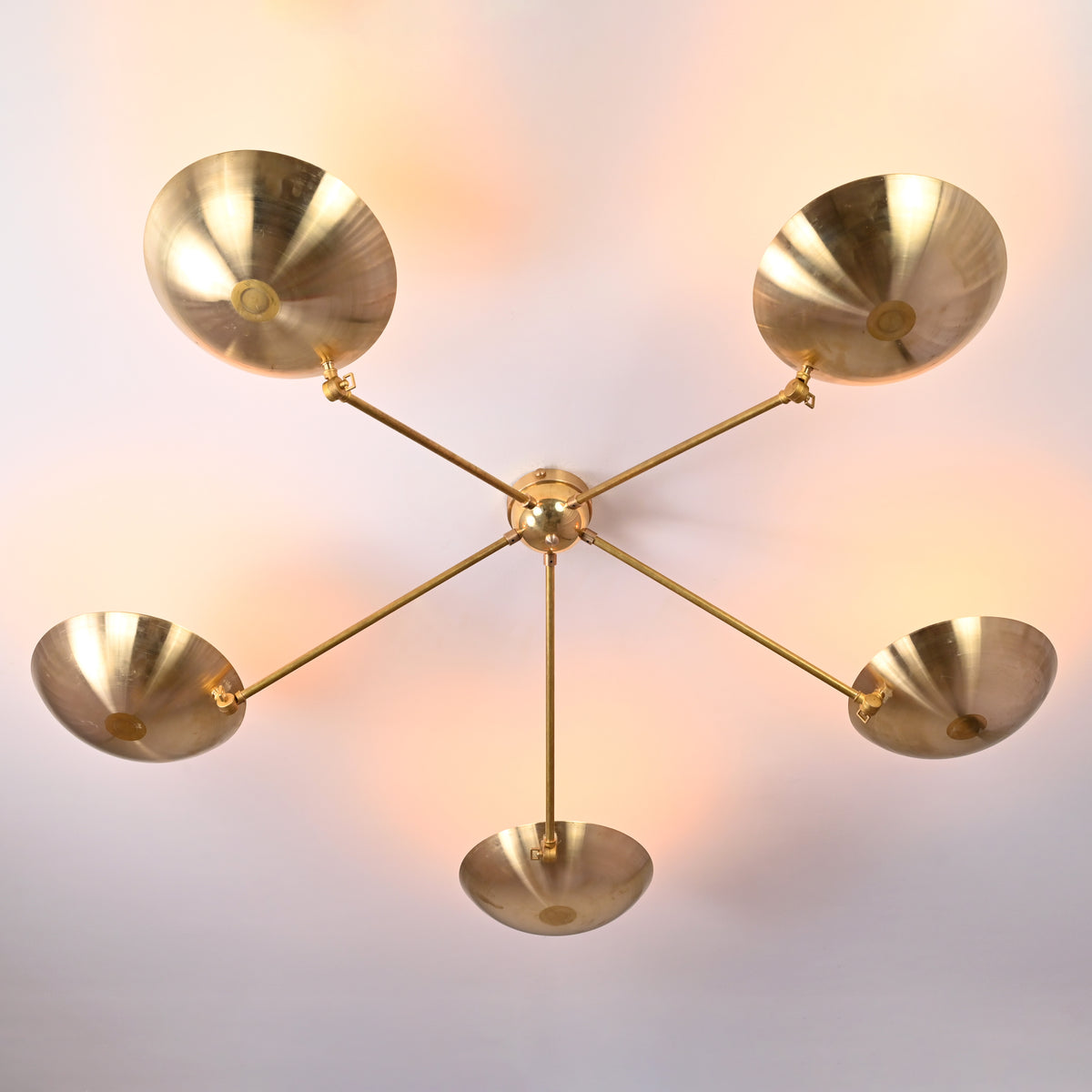 Bottom view of modern 5-light brass chandelier with sculpted bowl shades creating soft ambient light.