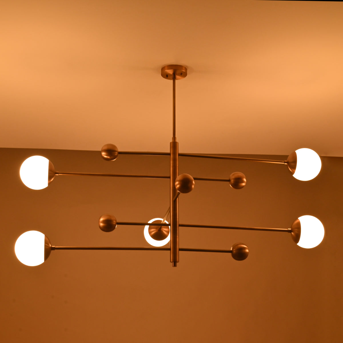 Warm ambient glow from a 5-light brass chandelier featuring opal globes and sculpted linear brass arms.