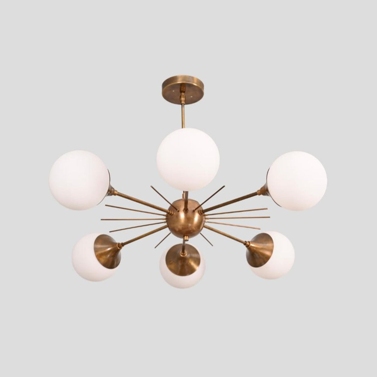 Contemporary Sputnik-style brass chandelier with six spherical white glass globes, creating an elegant ambient glow for modern interiors.