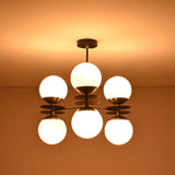 Ceiling view of glowing 6-globe chandelier with opal glass globes in warm brass and black finish