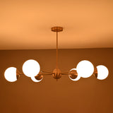 Night view of 6-light brass chandelier illuminated with warm ambient lighting from frosted glass globes.