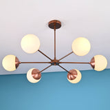 Angled view of handcrafted 6 light glass globe brass chandelier with brushed brass finish and opal glass globes