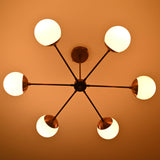 Illuminated 6 light glass globe brass chandelier highlighting brushed brass arms and soft diffused light