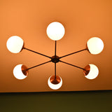 Warm lit 6 light glass globe brass chandelier showcasing symmetrical mid-century design and handcrafted brass details
