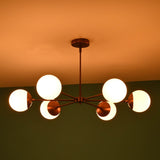 Angled night view of 6 light glass globe brass chandelier with glowing opal glass globes and elegant brass finish