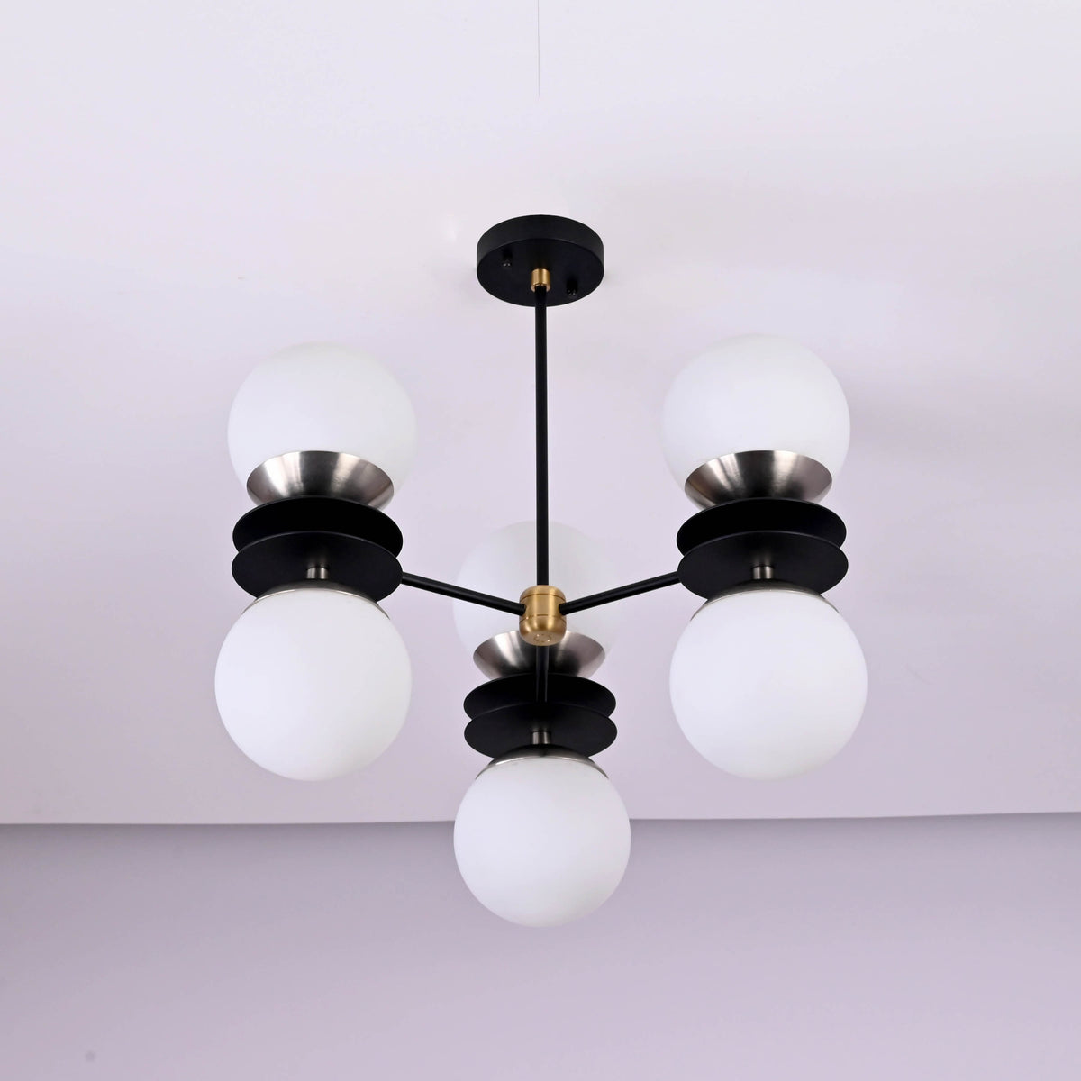 Bottom view of six light brass chandelier featuring opal glass globes and layered disc design