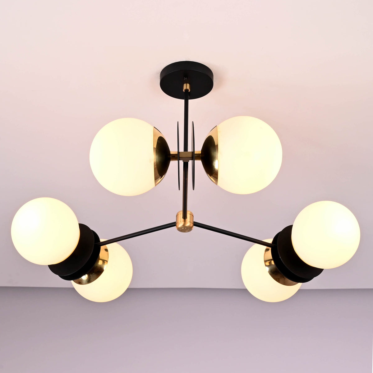 Close-up detail of opal glass globe shades and solid brass hardware on a modern industrial chandelier.