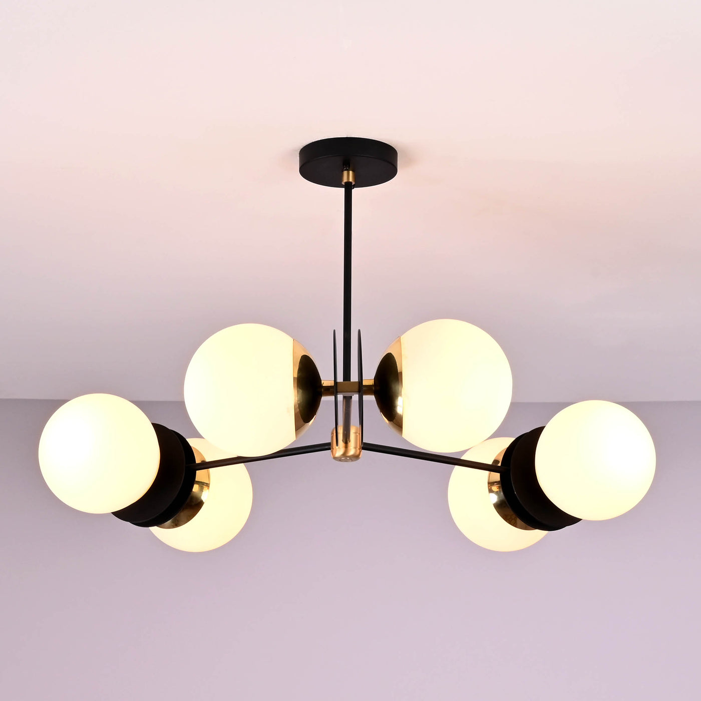 Front view of a 6 opal glass globe brass chandelier with black arms and brushed brass details, providing warm ambient ceiling lighting.