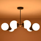 6-light opal glass globe brass chandelier illuminated in a warm ambient glow, creating a cozy modern interior atmosphere.