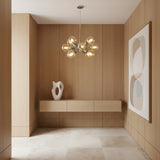 A modern multi-light cluster chandelier with eight clear glass globe bulbs on a brushed brass or gold-toned metal frame, suspended by a single rod against a plain white background.