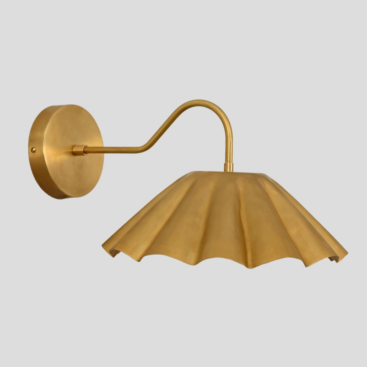 Golden brass pleated shade wall sconce with round backplate and curved arm – handcrafted wall light fixture.