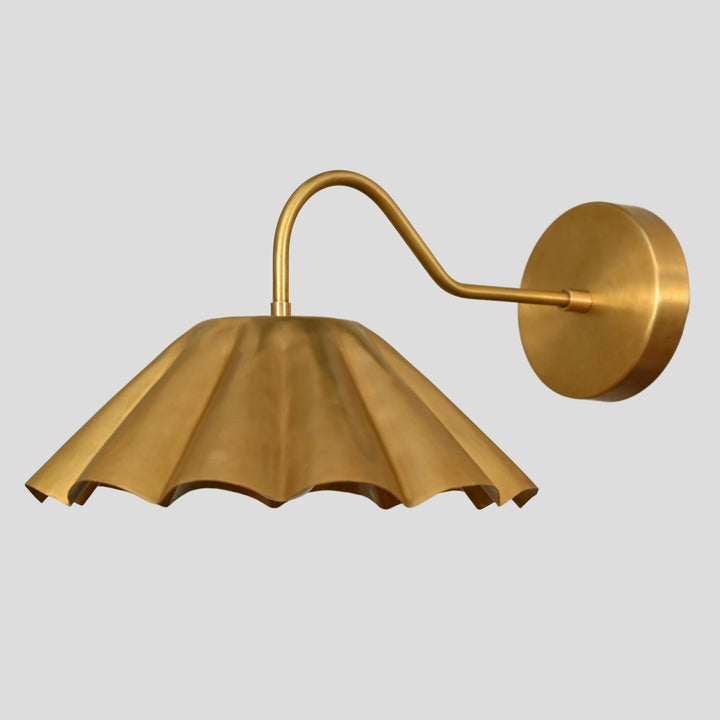 Side profile of handmade golden brass pleated wall sconce with sculpted shade and curved brass arm.