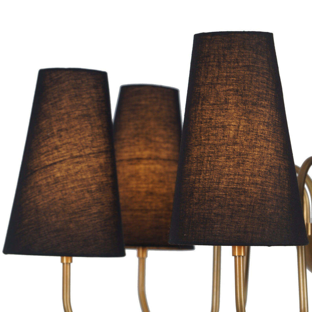 Close-up detail of textured black fabric shades on a brass chandelier, highlighting the soft warm light glow through the fabric.