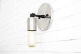 Brushed nickel wall sconce with round backplate and capsule Edison bulb, modern minimalist industrial style on white tile wall