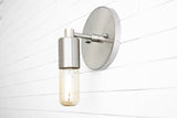 Modern brushed nickel wall sconce with cylinder socket and capsule Edison bulb on white subway tile background