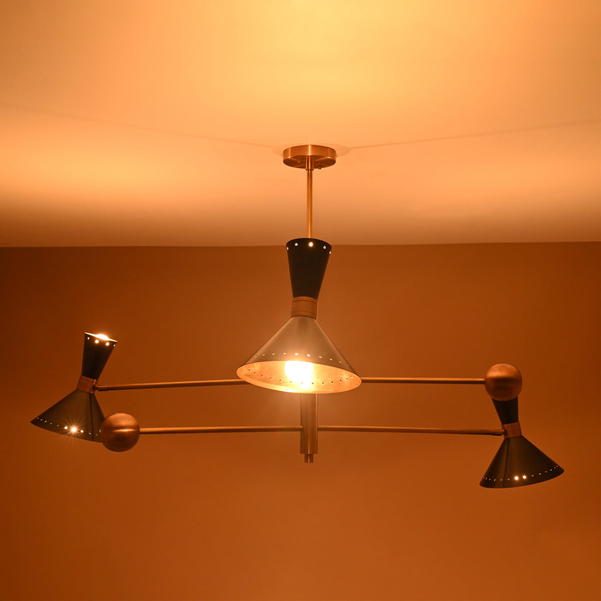 Illuminated brass and black 6 light cone chandelier glowing with warm ambient light