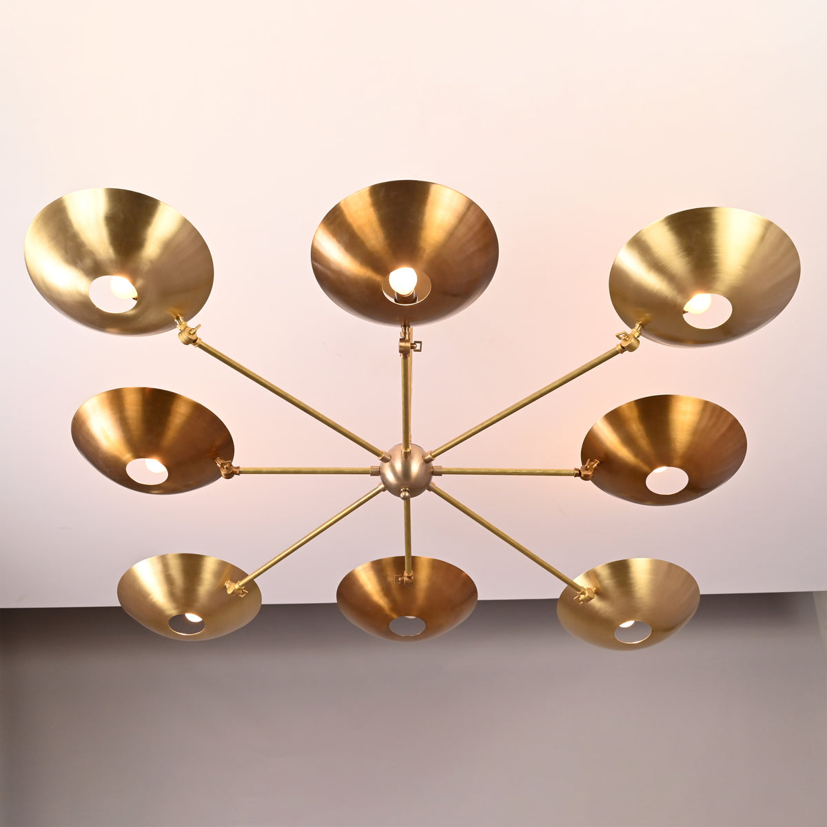 Bottom view of 8-light brass disc chandelier with radiating arms and circular brass shades.