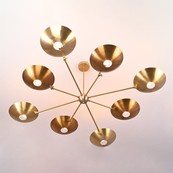 Wide-angle view of mid-century brass disc chandelier suspended from ceiling with eight brass dish shades.