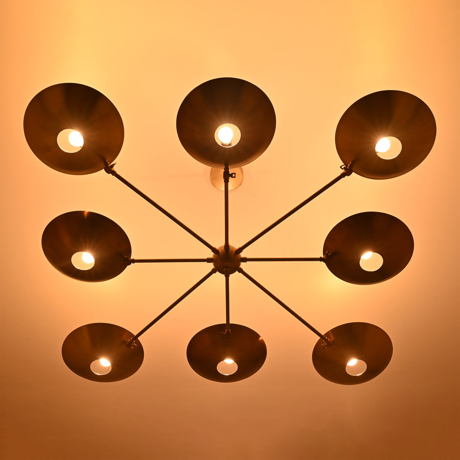 Wide-angle view of mid-century brass disc chandelier suspended from ceiling with eight brass dish shades.
