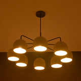 8-light brass chandelier glowing with warm ambient lighting, featuring dome-shaped shades and minimalist arms.