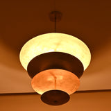 Elegant raw brass hanging light with tiered bowls creating soft ambient lighting