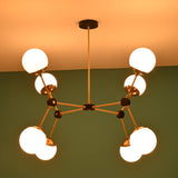 Close-up detail of brass arms, black connectors, and opal glass globe shade on an 8-light modern chandelier.