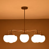 Warm-lit front view of brass chandelier with eight frosted globes creating a soft ambient glow.