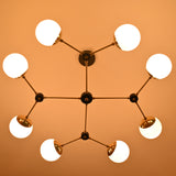 8-light brass globe chandelier illuminated with warm ambient lighting, showcasing opal glass shades and modern linear form.