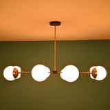 Wide view of an 8-light brass globe linear chandelier highlighting its extended horizontal spread and sculptural modern form.