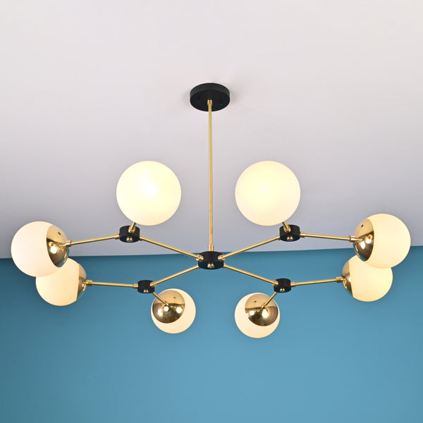 Front view of an 8-light brass globe linear sputnik chandelier with opal glass shades and black accents, suspended from the ceiling in a modern interior.