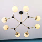 Angled view of an 8-light brass linear chandelier with opal globe shades and black joint details, highlighting its balanced modern design.