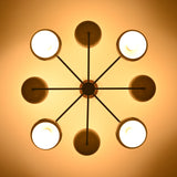Warm top-view photo of 8-light brass chandelier casting soft, diffused lighting through bowl-shaped shades.