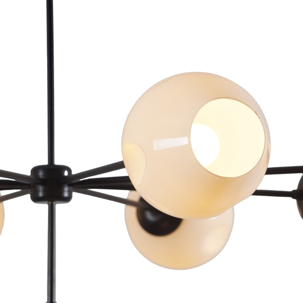 Close-up of sculpted white glass shade on 9-light modern brass chandelier showing detailed craftsmanship