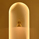 Adelaide brass cone wall sconce displayed in a warmly illuminated architectural niche with golden ambient lighting and elegant minimalist styling.