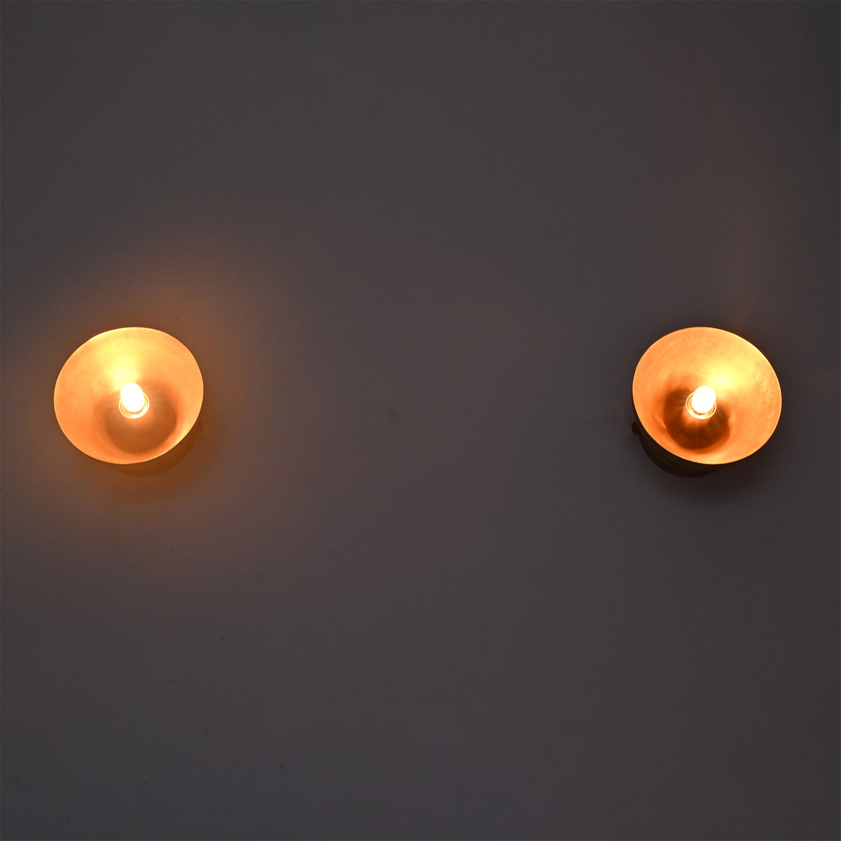 Pair of illuminated Alden Modern Dome Wall Sconces emitting a warm ambient glow with exposed decorative bulbs.