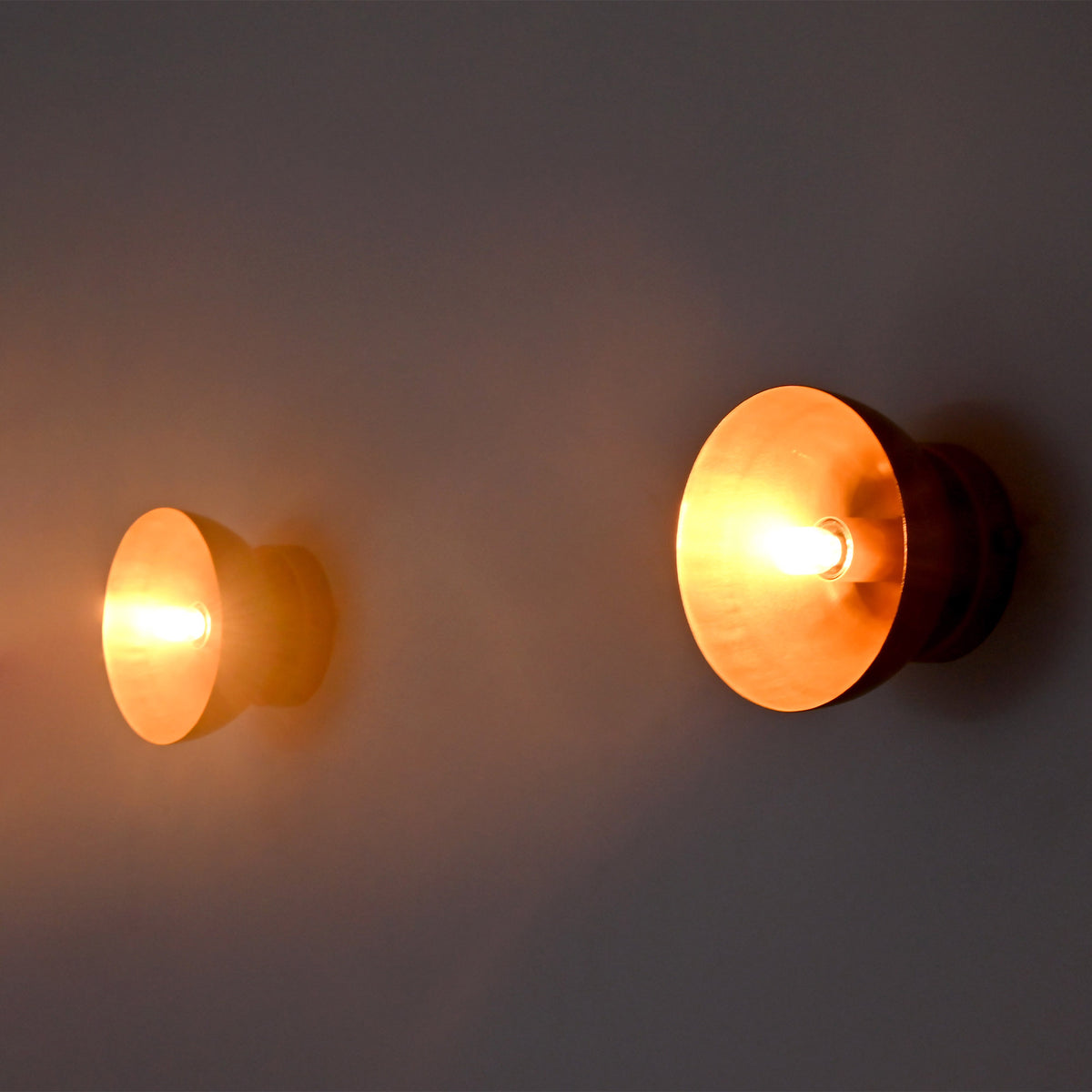 Side-angle view of two illuminated Alden Modern Dome Wall Sconces emphasizing their sculptural dome silhouette and warm lighting.