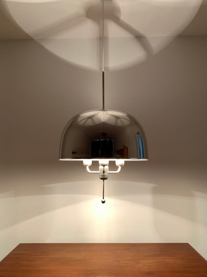 Illuminated Alexandria polished chrome dome pendant featuring a reflective hemispherical metal shade, exposed bulb arrangement, slender suspension, and warm ambient lighting.