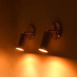 Modern antique brass directional wall sconce creating soft accent lighting with an adjustable cylindrical spotlight head.