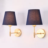 Angled view of the antique brass wall sconce with a rich blue tapered fabric shade, showcasing the slim brass arm and round wall backplate.