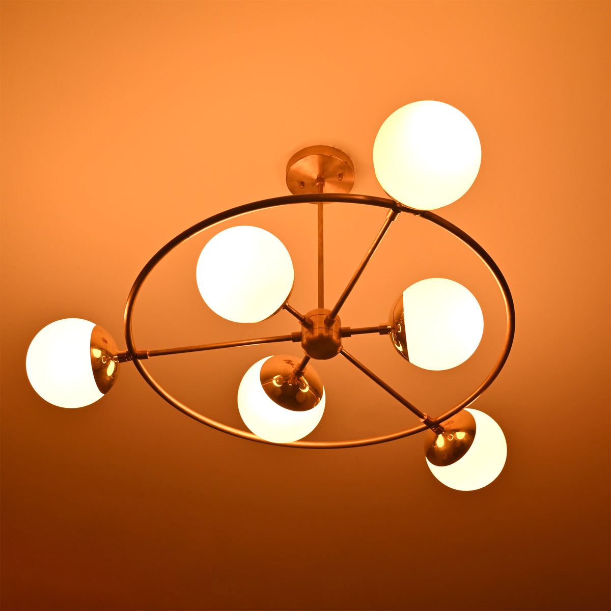 Aria Orbit Globe Chandelier installed on ceiling with warm glowing globe shades and sculptural orbital frame.
