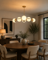 Aria Orbit Globe Chandelier above dining table in modern room with warm ambient lighting and globe shades.