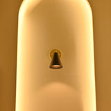 Aspen black tapered cone wall sconce displayed in a tall arched niche surrounded by warm golden ambient lighting.