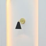 Aspen Mid-Century Modern black and brass wall sconce mounted inside a white architectural wall niche with soft warm ambient lighting.