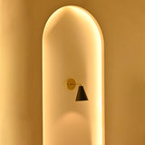 Aspen single-light black cone wall sconce with brass mounting plate displayed in a softly illuminated architectural niche during evening lighting.