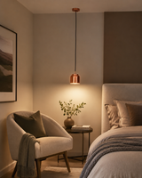 Aspen copper cylinder pendant light installed beside a modern bedroom, providing warm focused lighting above a bedside table in a contemporary interior.