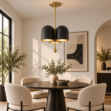 Athens 3 light black and brass-tone chandelier installed above a round dining table in a bright contemporary dining room.