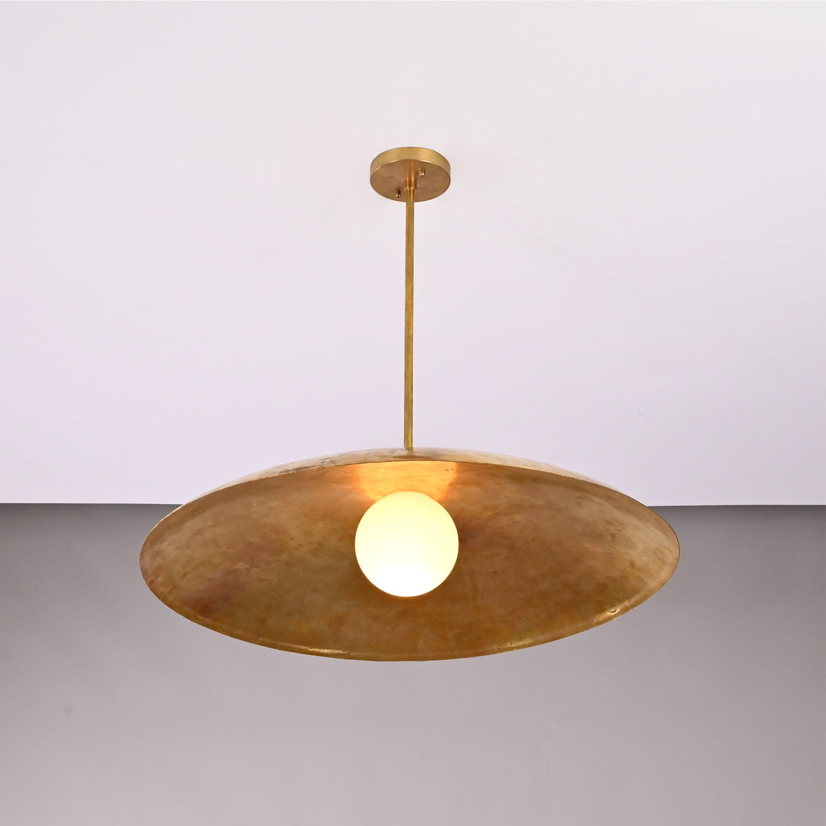 Angled view of Aurelia Globe Saucer Pendant Light showing broad saucer shade and slim ceiling rod.