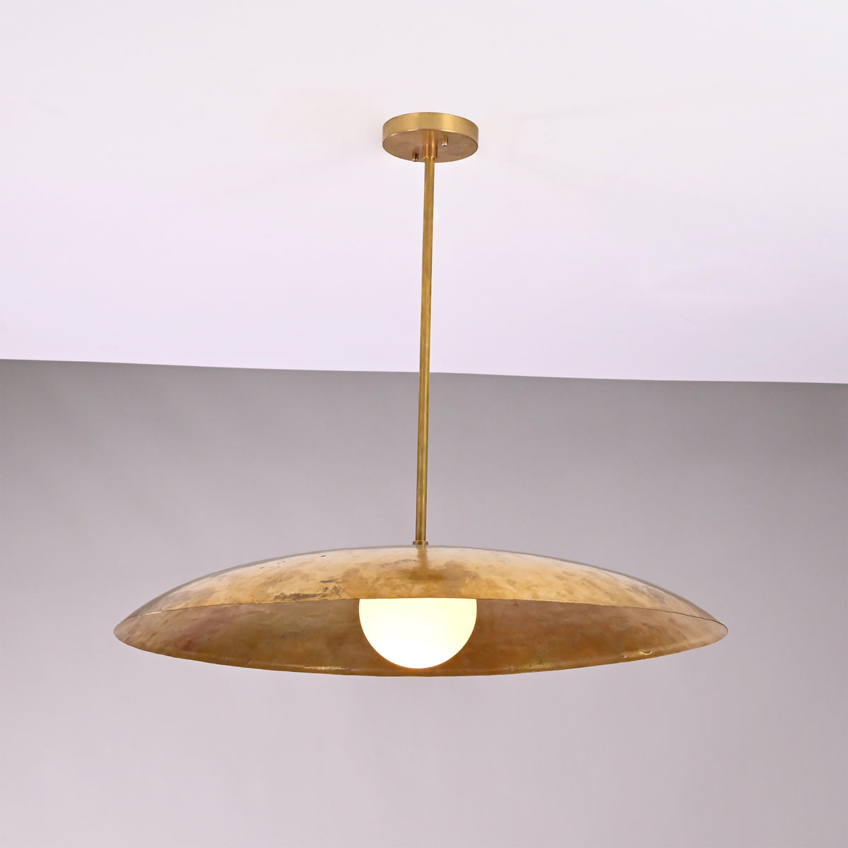 Front view of Aurelia Globe Saucer Pendant Light with wide dome shade and glowing globe bulb.