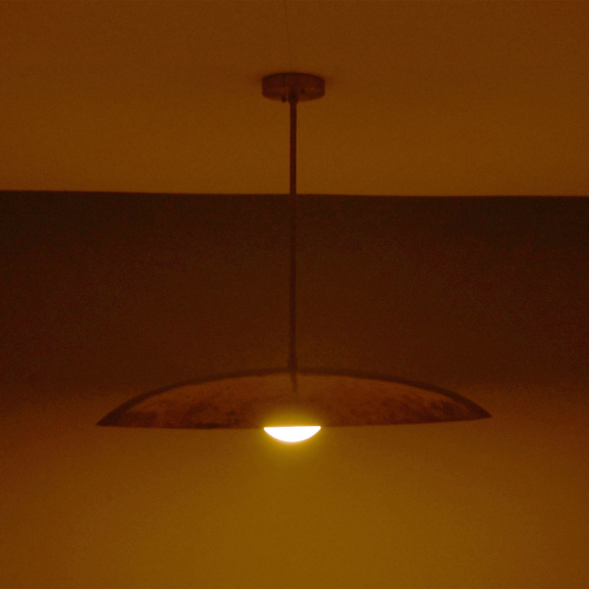 Side view of Aurelia Globe Saucer Pendant Light showing low saucer silhouette and downward warm glow.